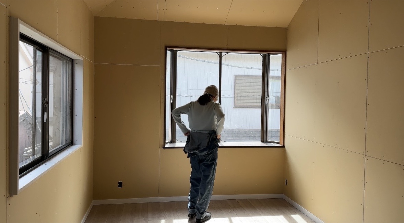 Minseon surveying progress in newly drywalled room